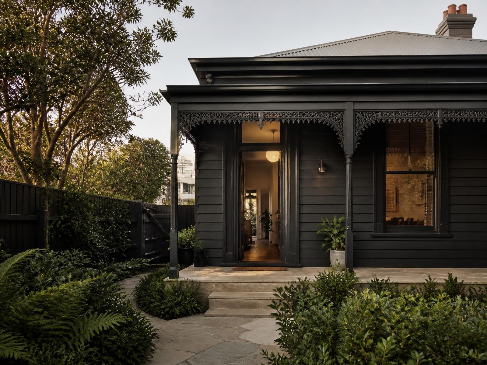 Renovated Melbourne home with charcoal weatherboard cladding and a bluestone path at dusk